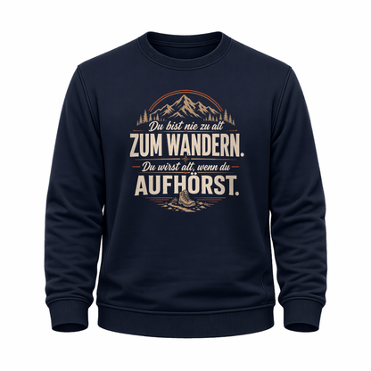 Navy blaues Wander-Sweatshirt mit Spruch „Du bist nie zu alt zum Wandern. Du wirst alt, wenn du aufhörst.“, Bergmotiv, Wald und Wanderschuh.